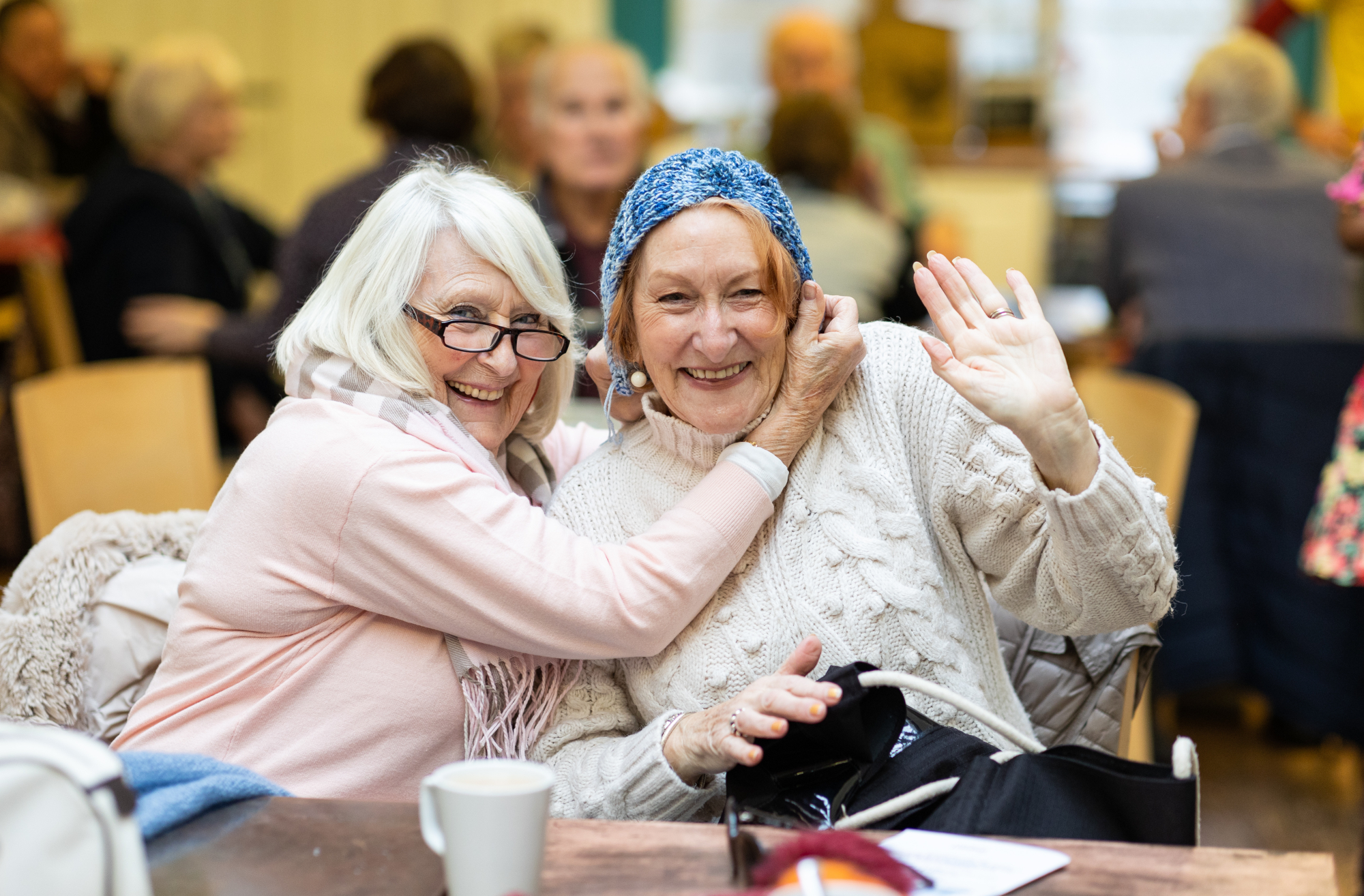 Two Smiling Older Women Playing Around With Their Knitting