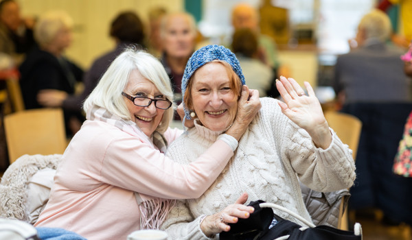 Two Smiling Older Women Playing Around With Their Knitting