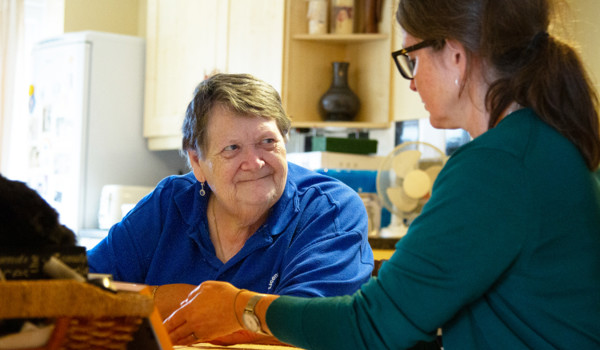Older Woman Smiling Whilst Woman Speaks To Her At Table