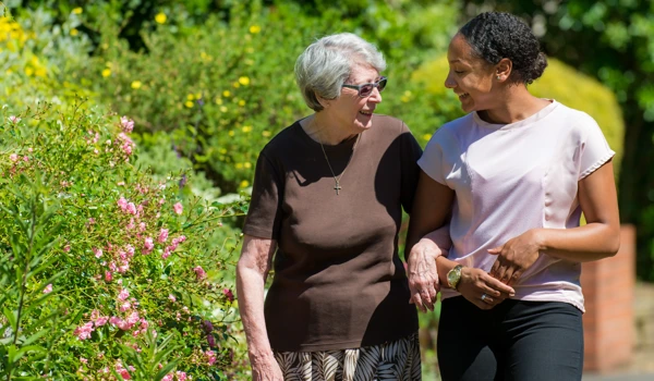 Older Woman And Member Of Staff Waking Together In Street