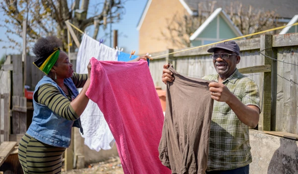 Woman Helping Older Man Put The Washing Out On The Washing Line