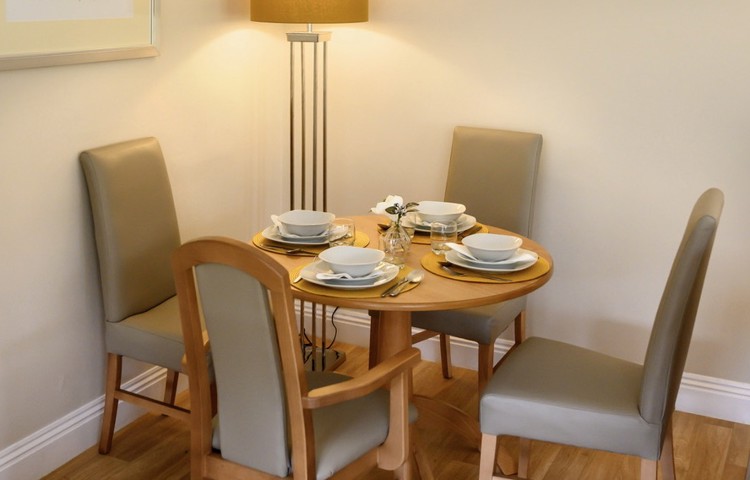 Dining table set for dinner with a tall lamp lit in the background