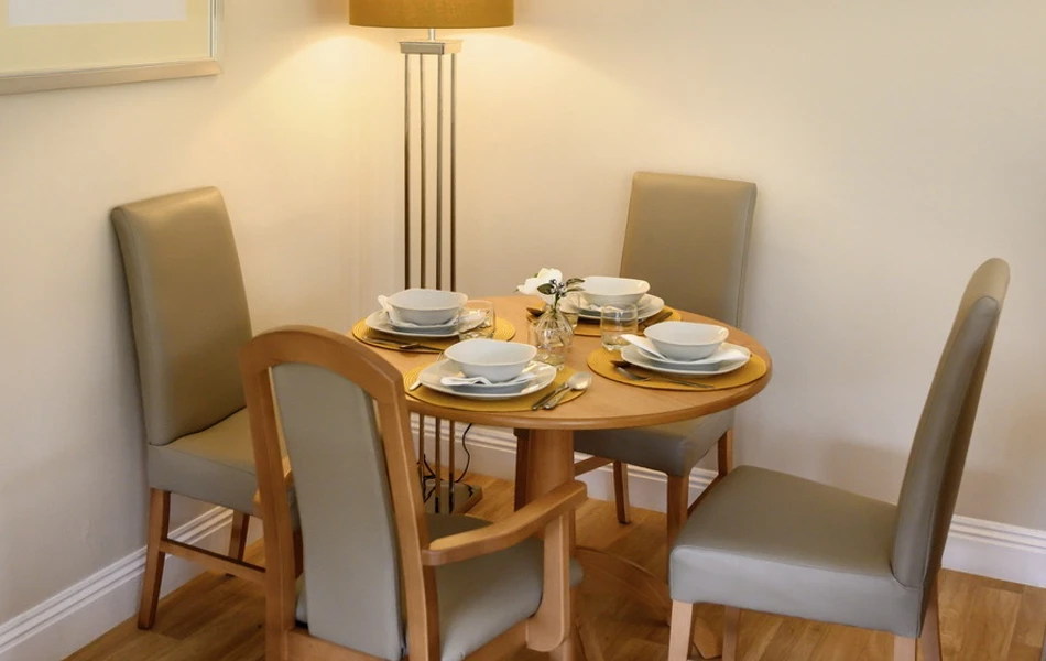 Dining table set for dinner with a tall lamp lit in the background