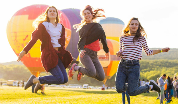 Group Of Women Jumping In Front Of Hot Air Balloons