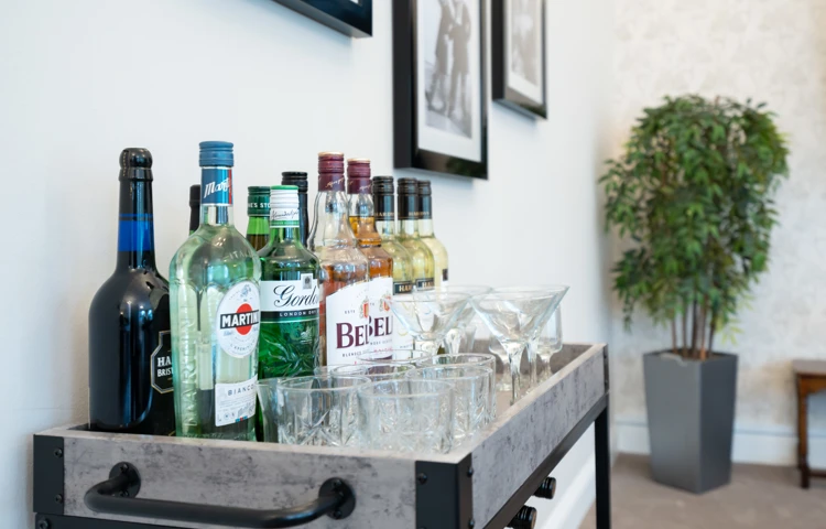 Assorted bottles of spirits and wine on a drinks trolley with glassware at Westall House Residential Care Home in Horsted Keynes.
