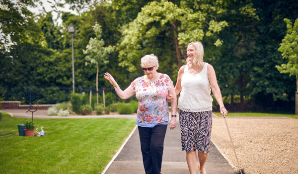 Two Women Walking Dog In Beautiful Sunny Garden
