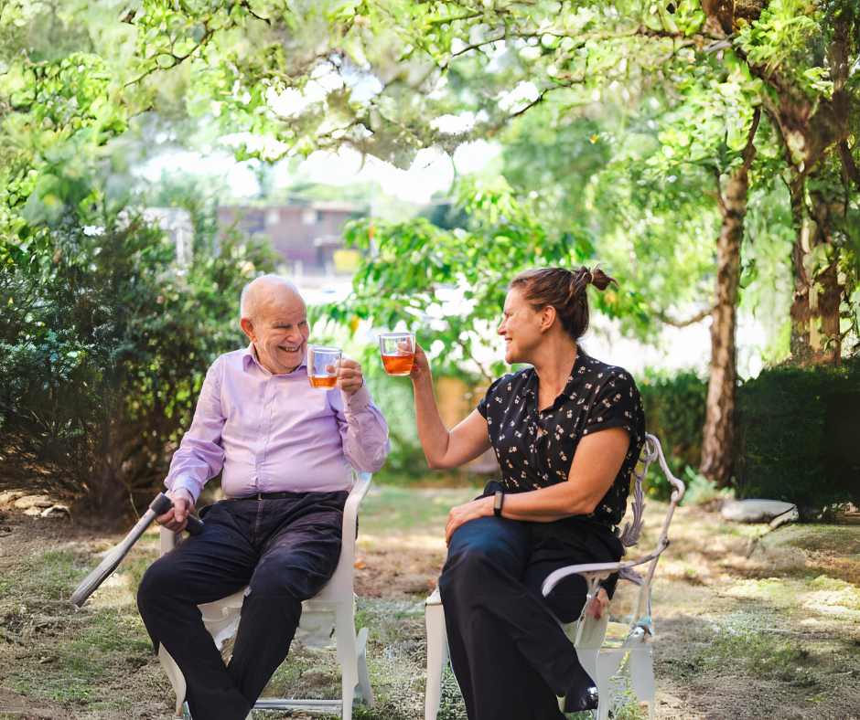 Older Man And Woman Enjoying A Drink Together In The Garden