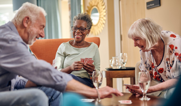 Group Of Older People Sitting Round A Table Playing Cards