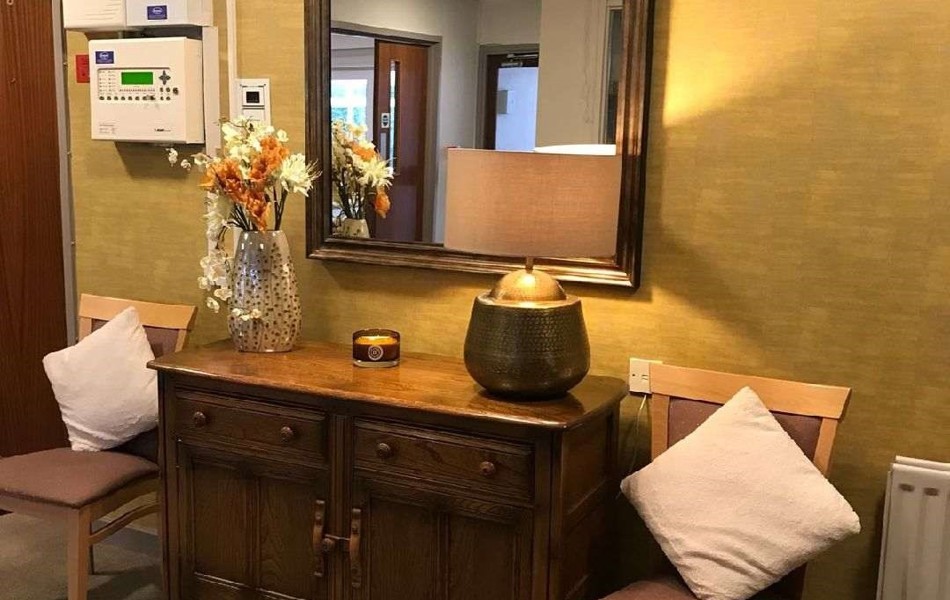 A desk and chairs in the entrance with a lamp