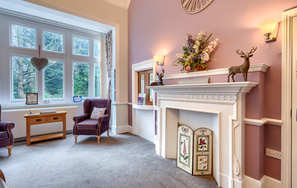 Interior of Westall House Residential Care Home sitting room with fireplace, armchairs, and large window.