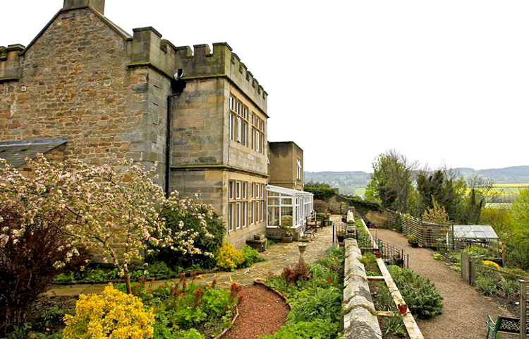 A grand stone building with turrets and beautiful gardens