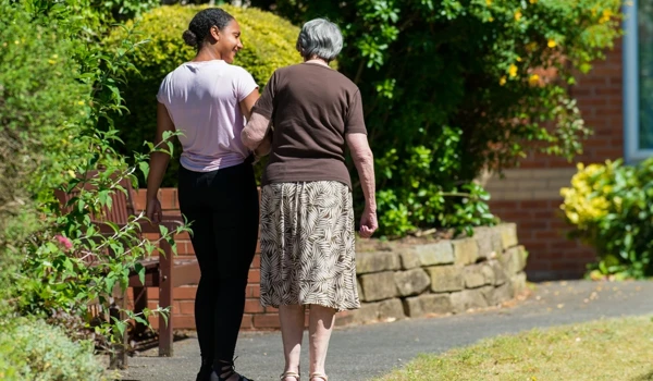Reisdent And Staff Member Take A Walk In The Beautiful Sunny Garden