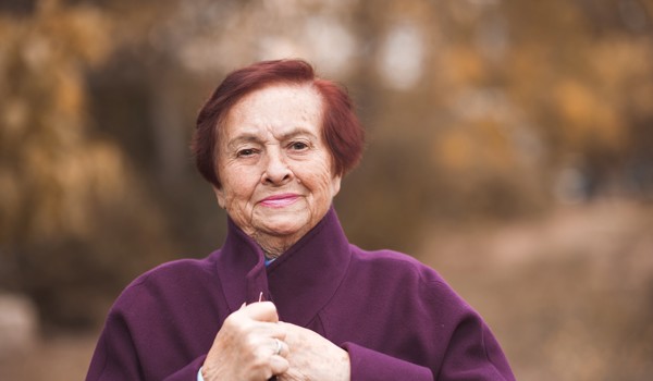 Smiling Older Woman Wrapped In Coat In Autumn