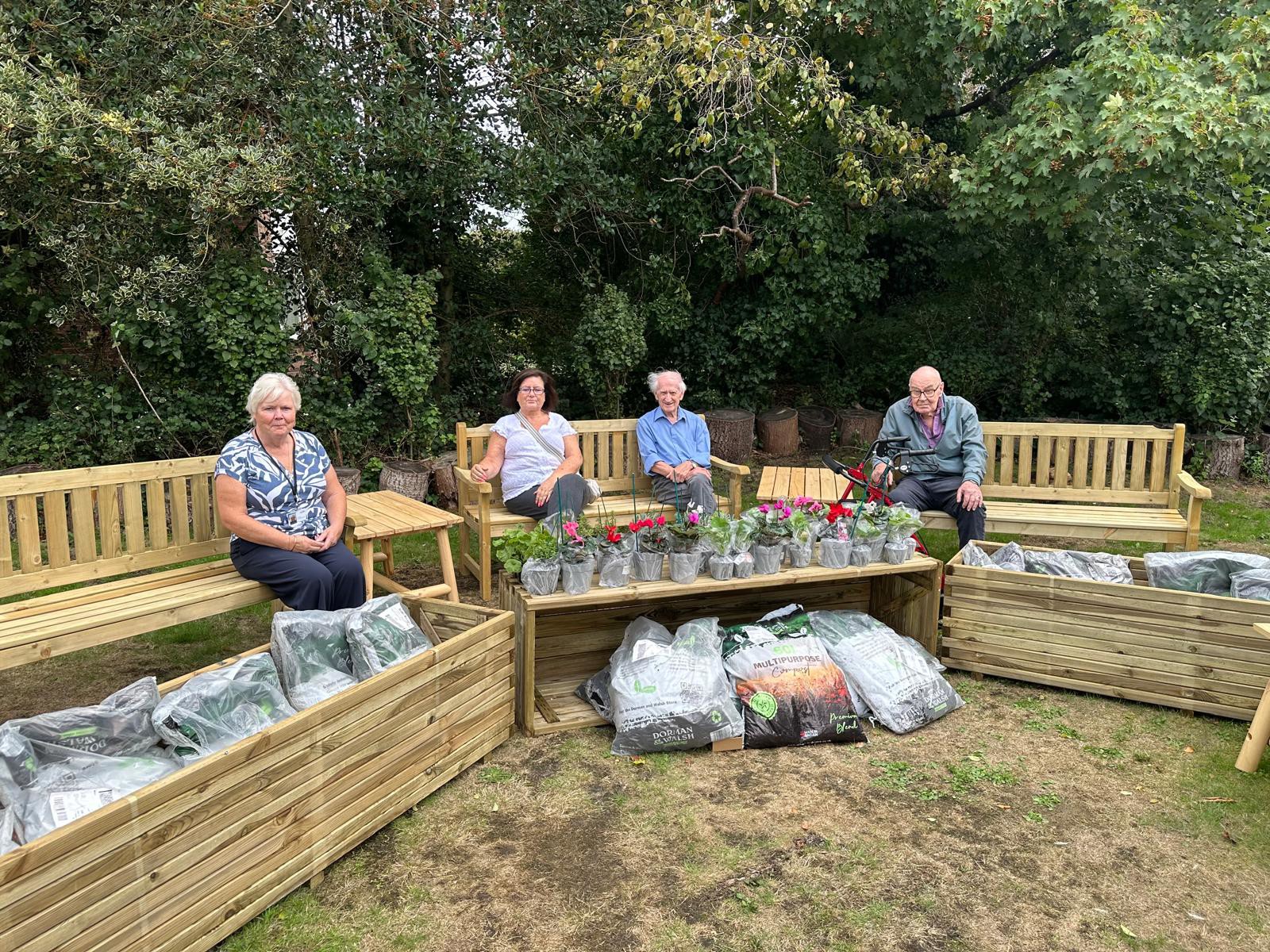 Linda and residents in the garden with the furniture and plants donated from Dodds Group