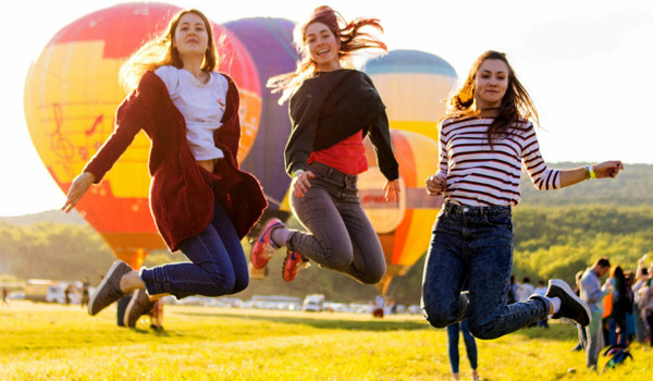 Group Of Women Jumping In Front Of Hot Air Ballooons