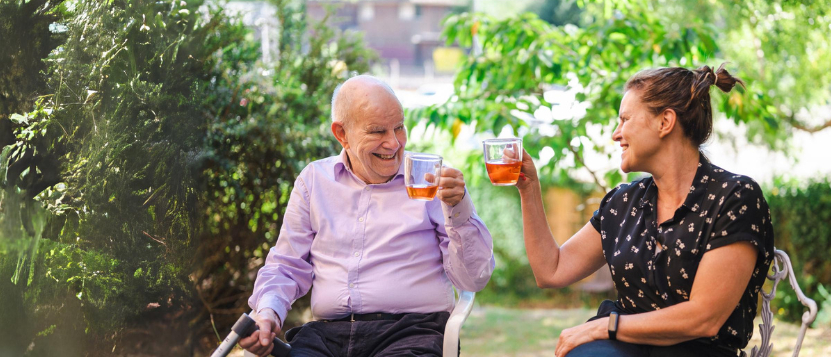 Smiling Woman And Older Man Enjoying A Drink In The Garden (2)