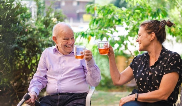Smiling Woman And Older Man Enjoying A Drink In The Garden (2)