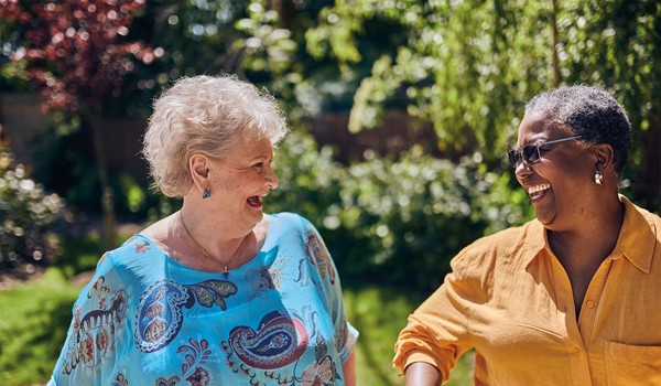 Two Older Women Laughing Together In Sunny Garden
