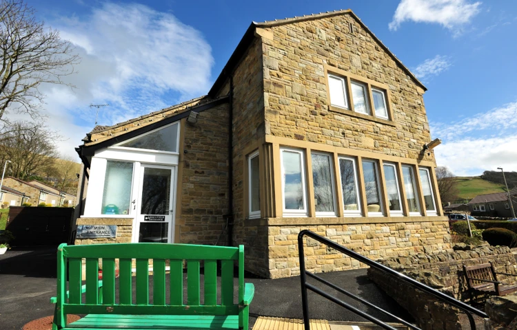 A green garden bench outside the front entrance of Abbeyfield House, Settle