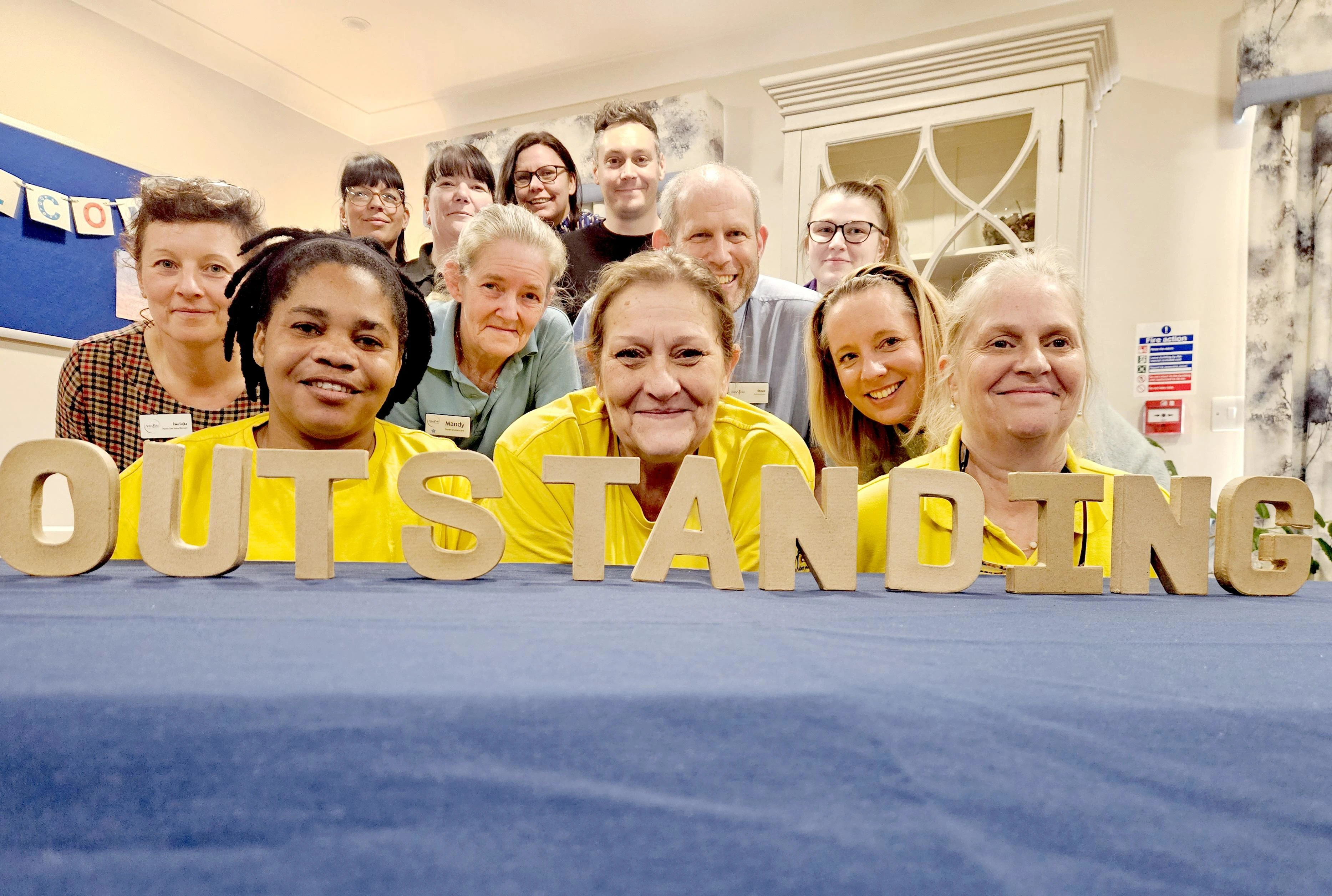 Speedwell Court staff standing in front of wooden outstanding sign