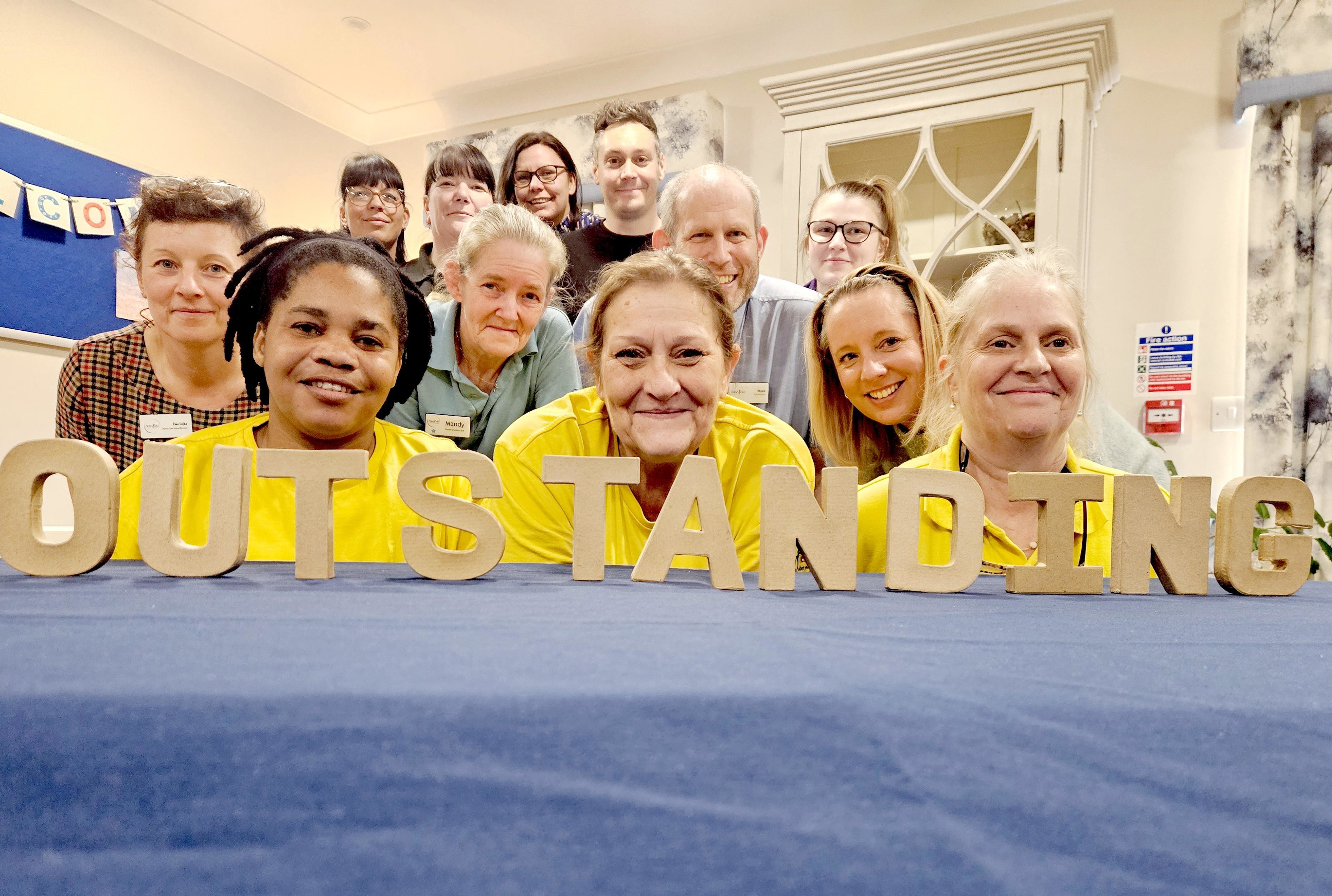 Speedwell Court staff standing in front of wooden outstanding sign