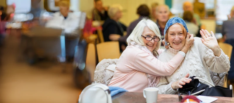 Two Older Women Sitting Together Having Fun At A Craft Club