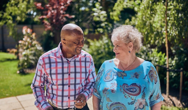 Older Man And Woman Chatting Together On A Walk In A Sunny Garden