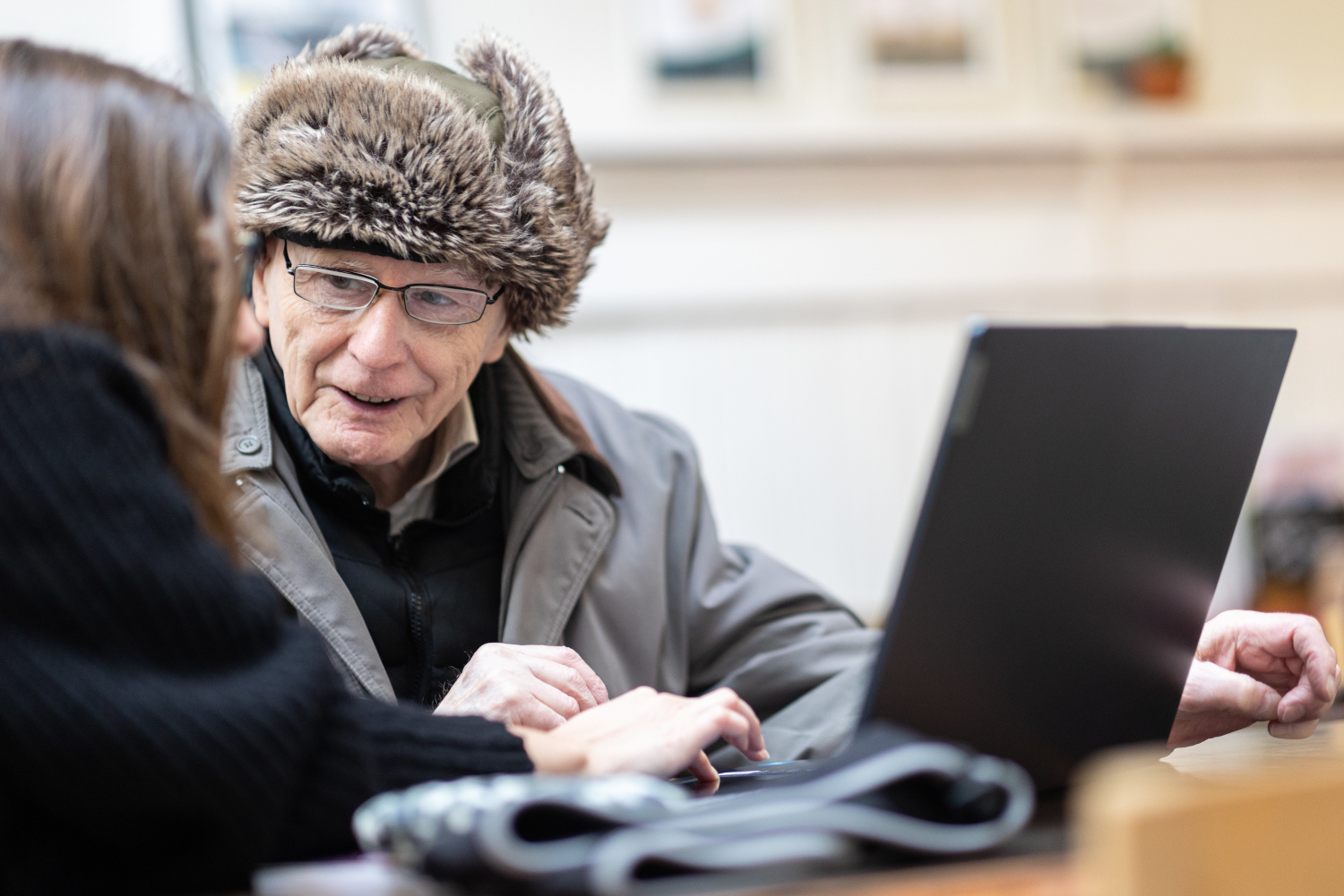 Woman Showing Older Man Something On Laptop