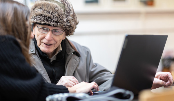 Woman Showing Older Man Something On Laptop