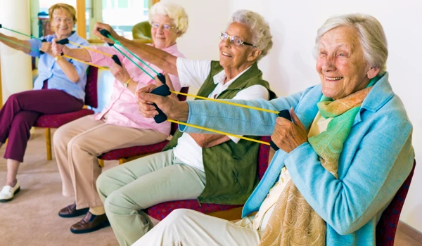 Group Of Older Residents Enjoying A Seated Keep Fit Class